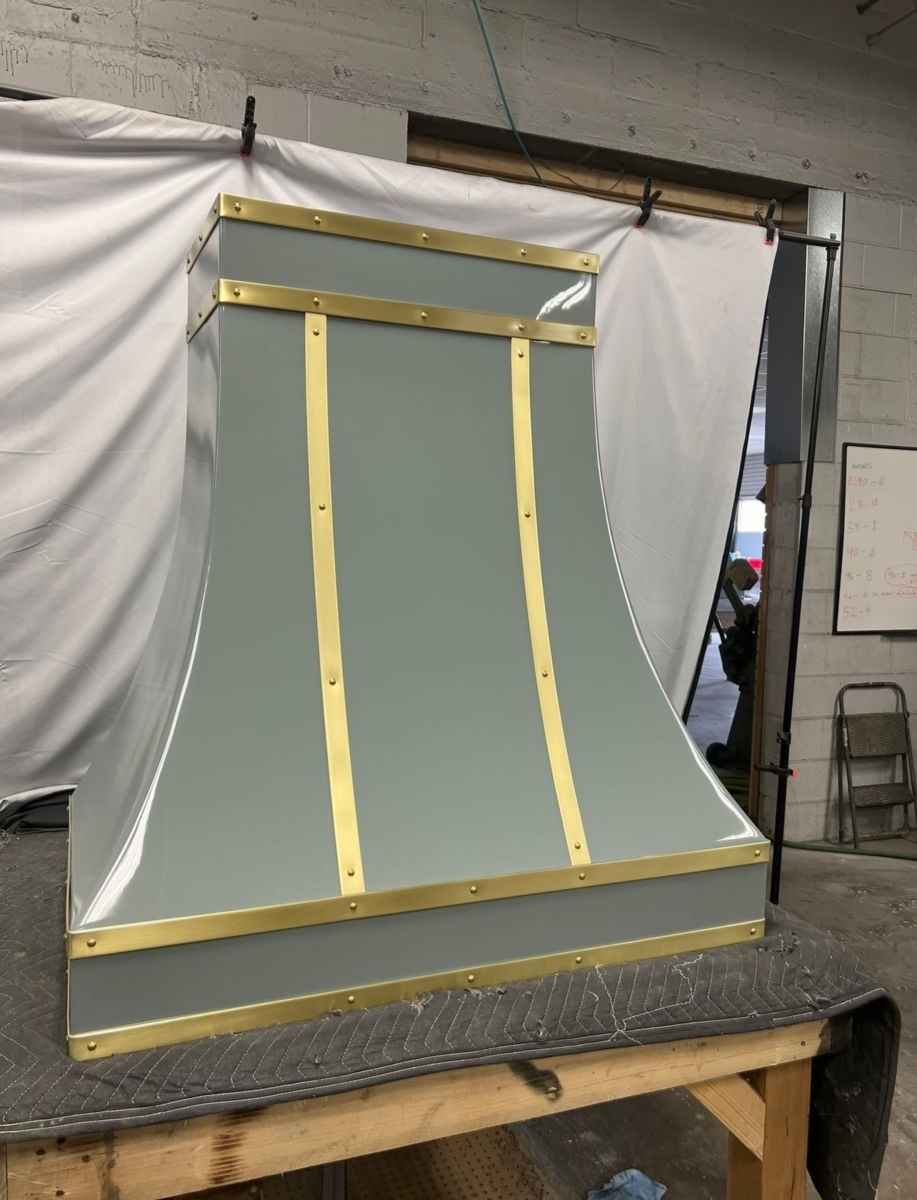 Curved gray panel framed with yellow tape on a workbench in a workshop
