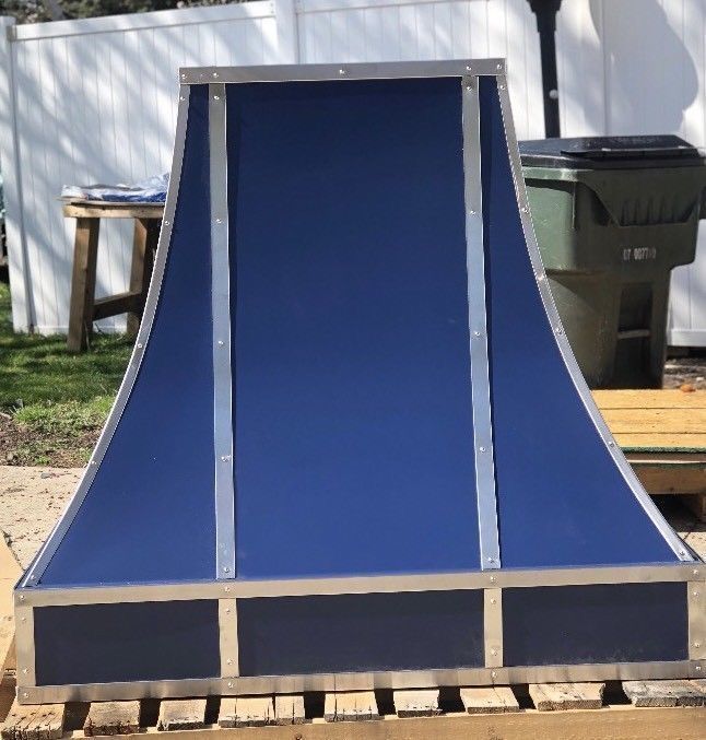 Blue wooden outdoor ramp or chute on a pallet in a yard, with a white building in the background