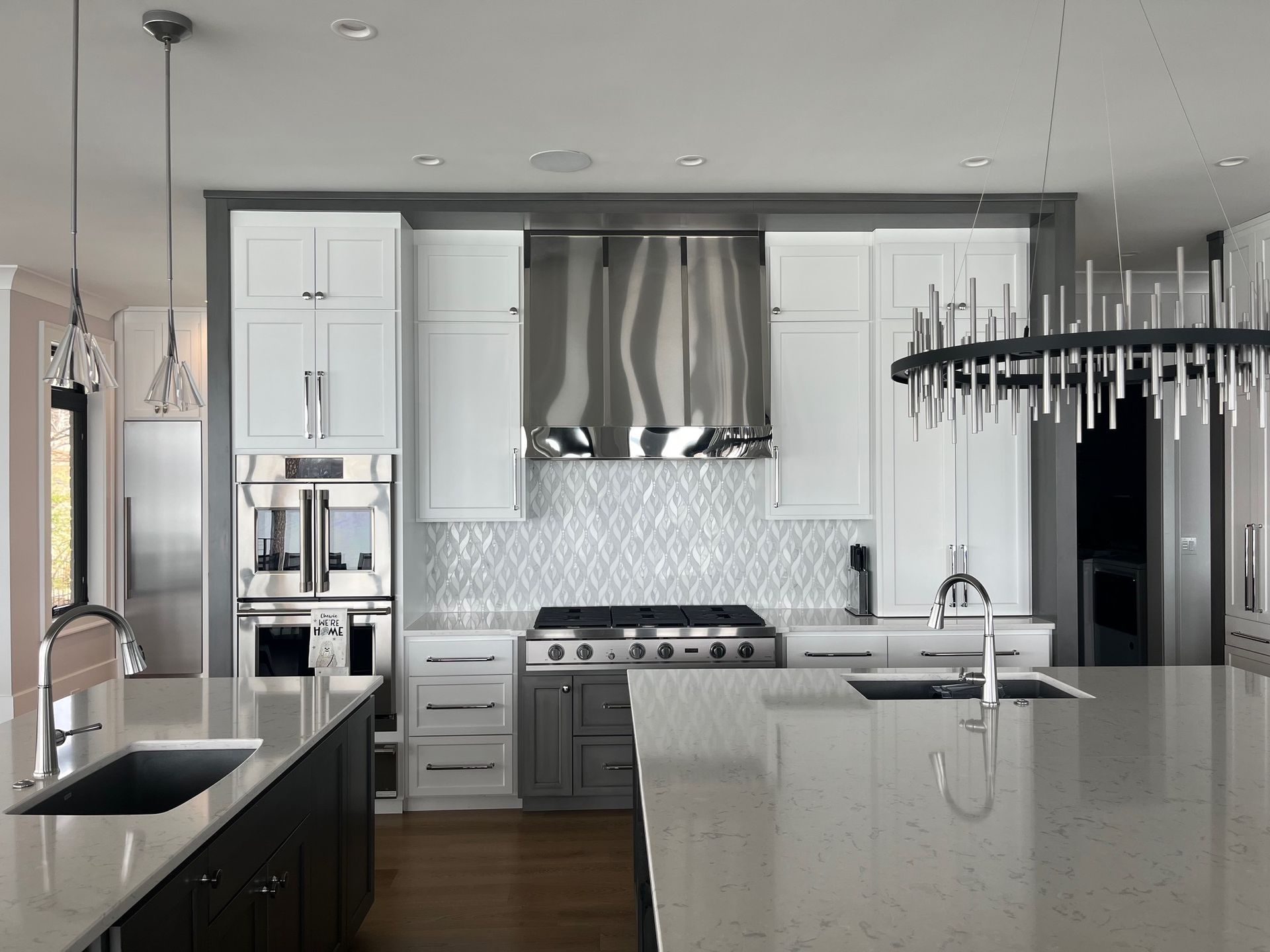 Bright modern kitchen with dark island, large windows, brick accents, and warm wood flooring