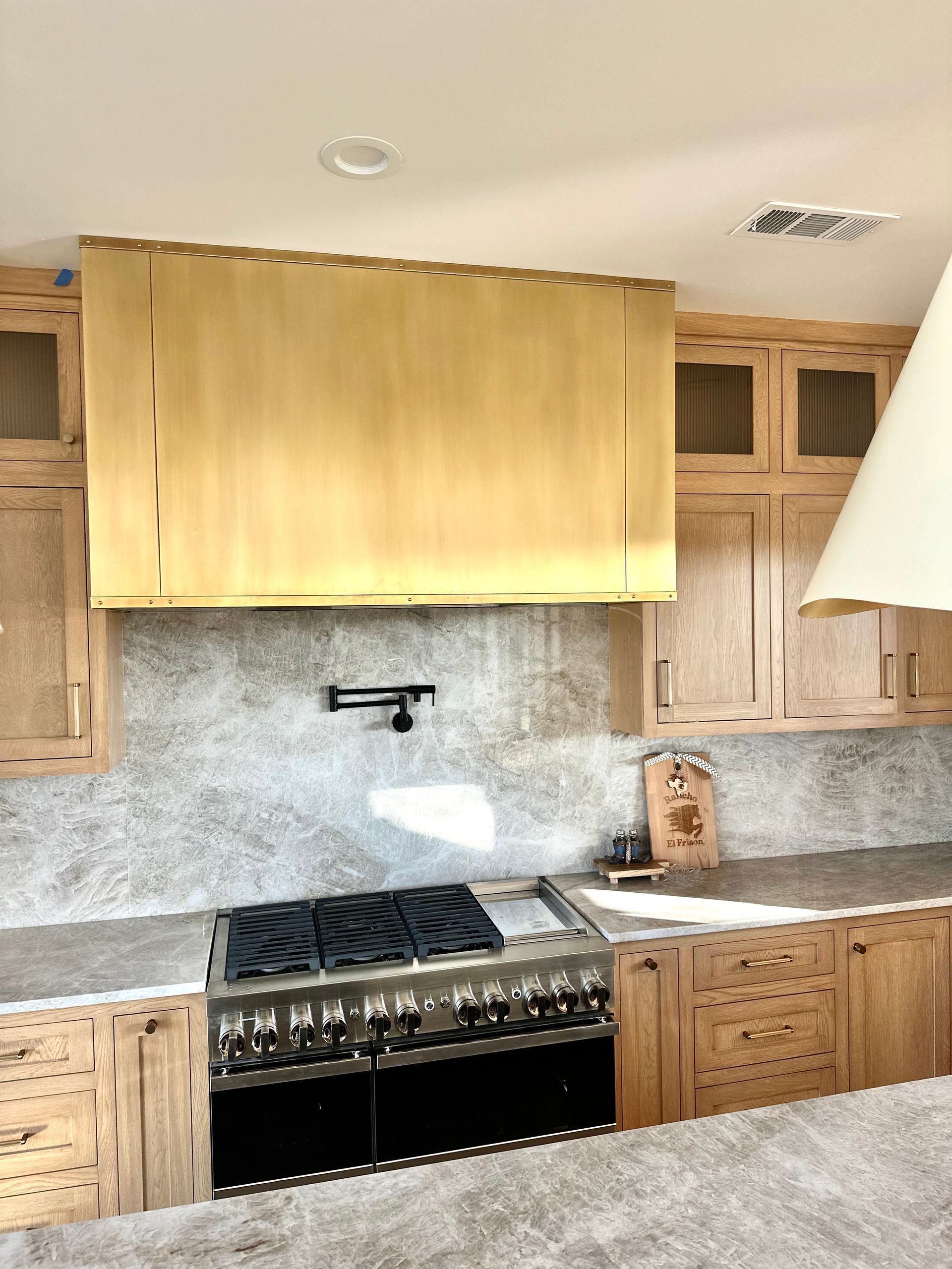Modern kitchen with black stove, wood cabinets, and a yellow window shade above the backsplash