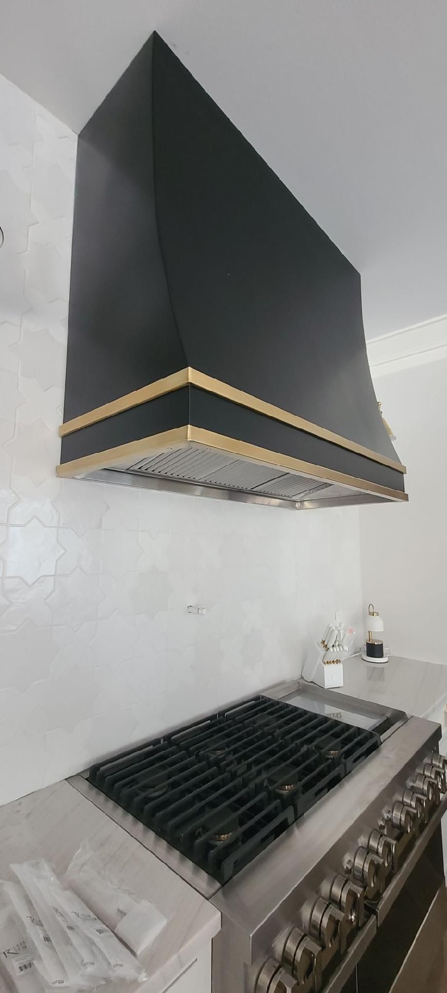 Modern kitchen with black range hood above a gas stove and stainless steel oven.