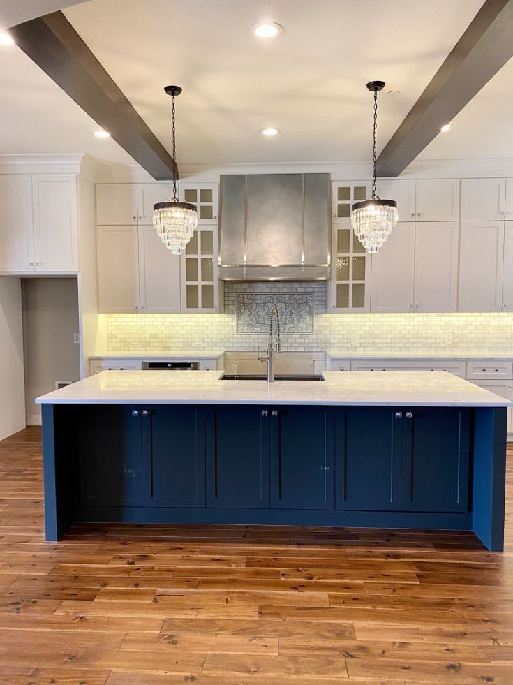 Modern kitchen with navy island, white cabinets, pendant lights, and hardwood floor