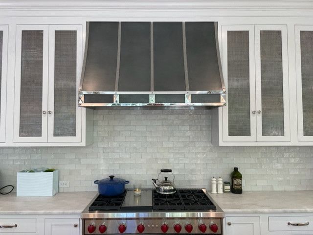 Modern kitchen with white cabinets, stainless range hood, gas stove, and blue pot on the counter