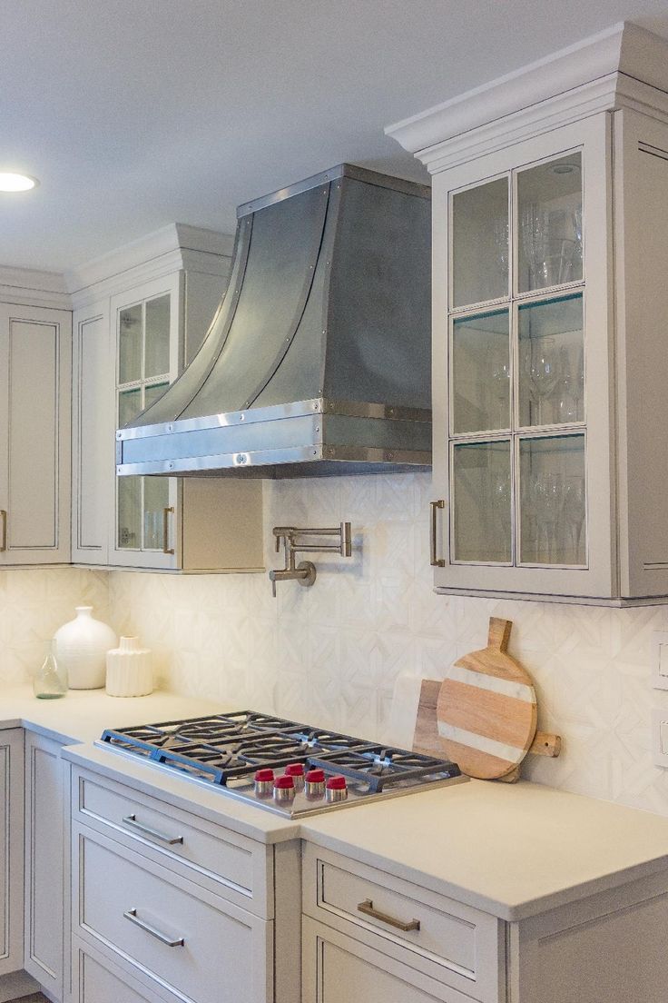 Modern white kitchen with stainless range hood, gas stove, and cream cabinets