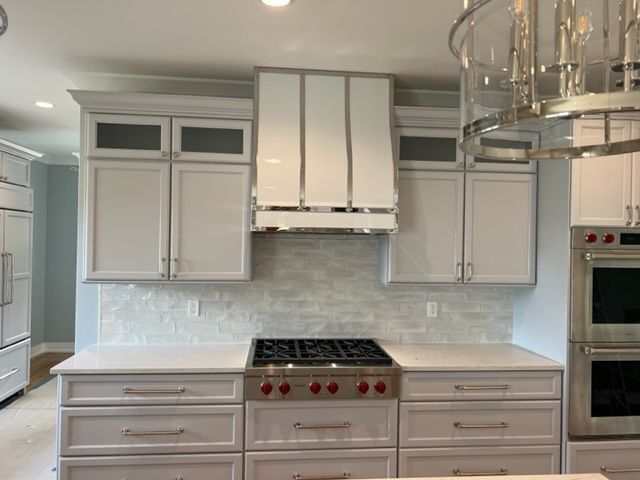 Bright modern kitchen with white cabinets, stainless steel range, and glass chandelier