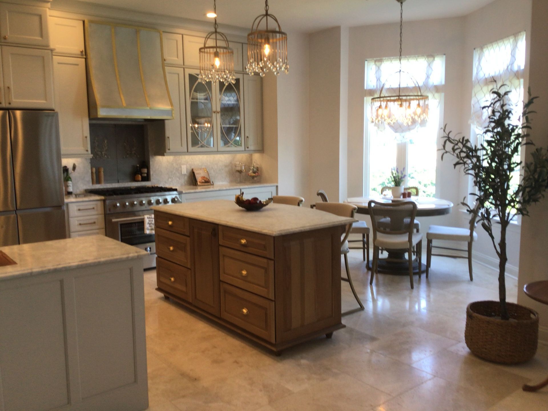 Modern kitchen with island, stainless steel appliances, and a dining nook by bright windows
