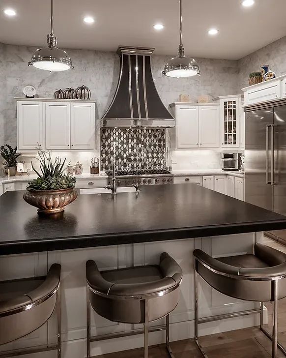 Modern kitchen with large island, stainless appliances, white cabinets, and three bar stools