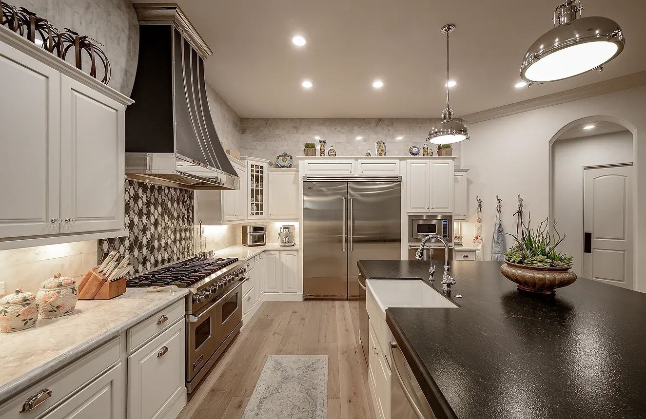 Bright modern kitchen with white cabinets, stainless steel appliances, and dark island countertop