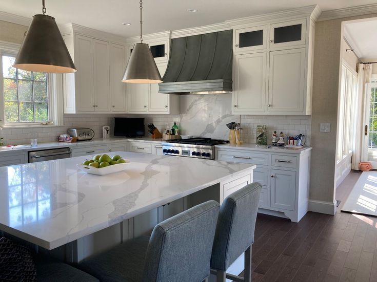 Bright modern kitchen with white cabinets, marble island, and two pendant lights