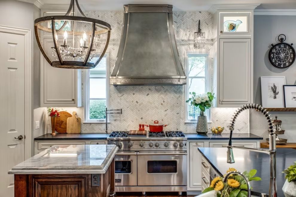 Bright modern kitchen with a stainless steel range hood, island, and pendant light above the sink.