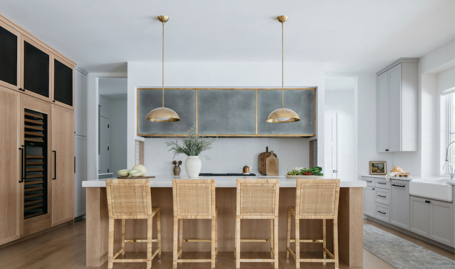 Bright modern kitchen with wood island, four stools, pendant lights, and stainless steel appliances.