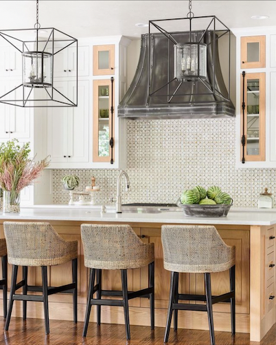 Modern kitchen with woven barstools, white counters, black pendant lights, and a tiled backsplash