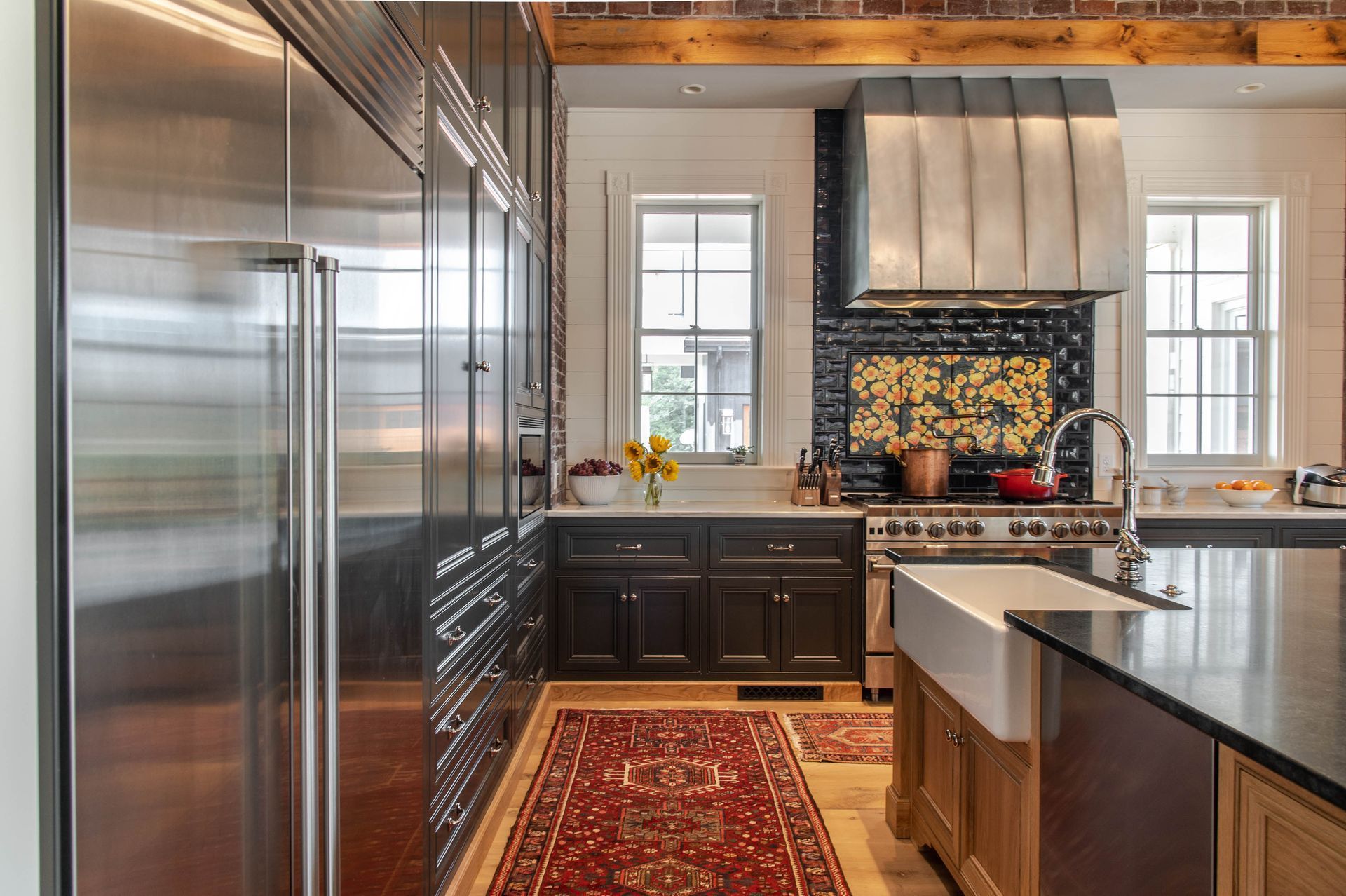 Modern kitchen with stainless steel appliances, dark cabinets, and a red patterned rug