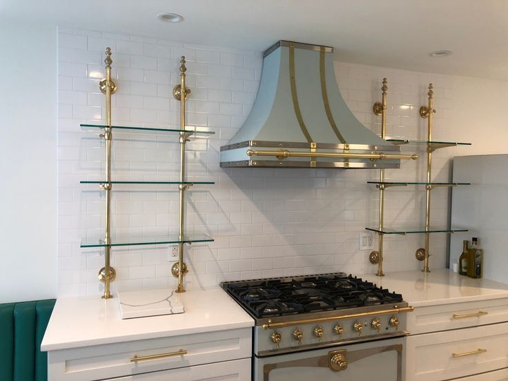 Modern kitchen with stainless steel stove, brass shelving, and a blue-and-gold range hood
