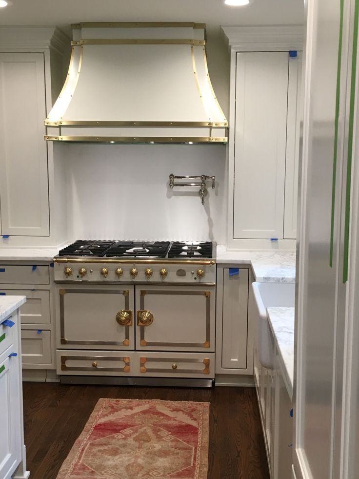 Bright kitchen with a stainless steel range, white cabinetry, and a red rug on dark wood flooring.