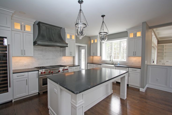 Bright modern kitchen with gray island, white cabinets, stainless appliances, and hanging pendant lights