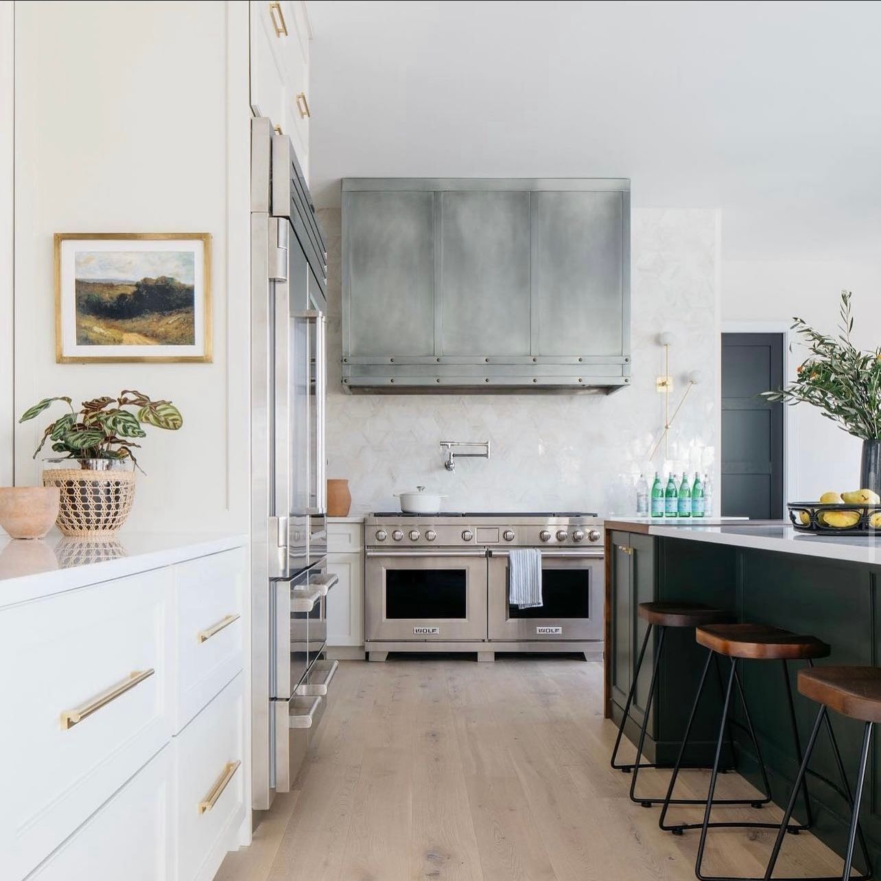 Bright modern kitchen with stainless stove, white cabinets, green island, and barstools
