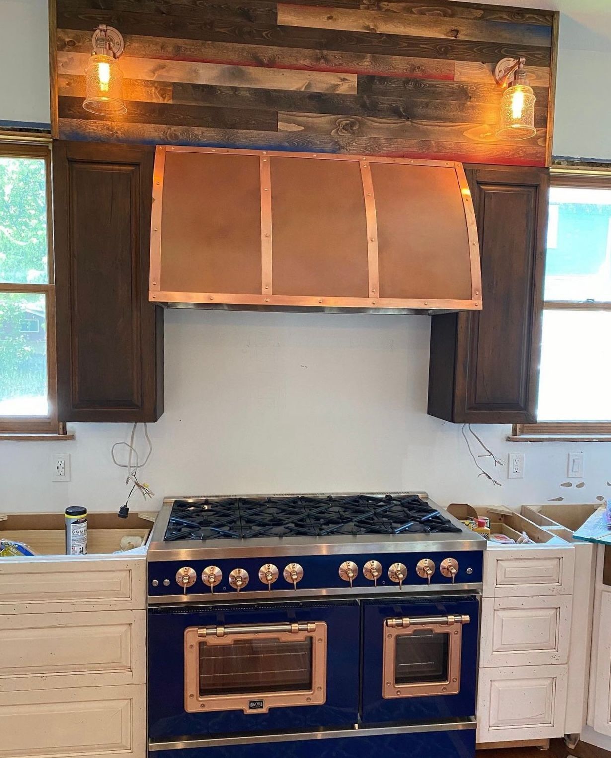 Rustic kitchen with a blue stove, copper range hood, and wood-paneled wall accents