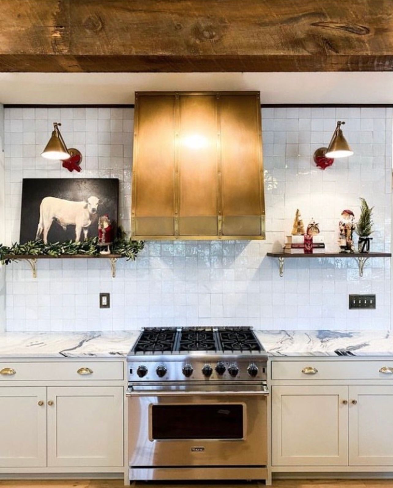 Modern kitchen with stainless steel stove, white cabinets, marble backsplash, and gold range hood