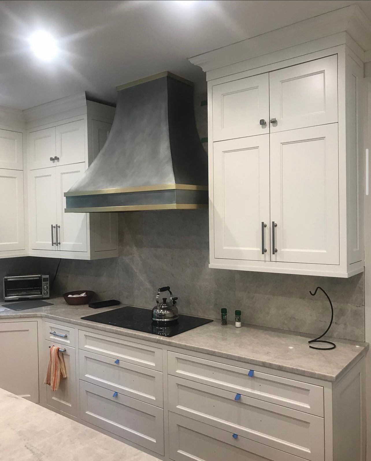 Modern kitchen with white cabinets, gray range hood, and marble-look countertops