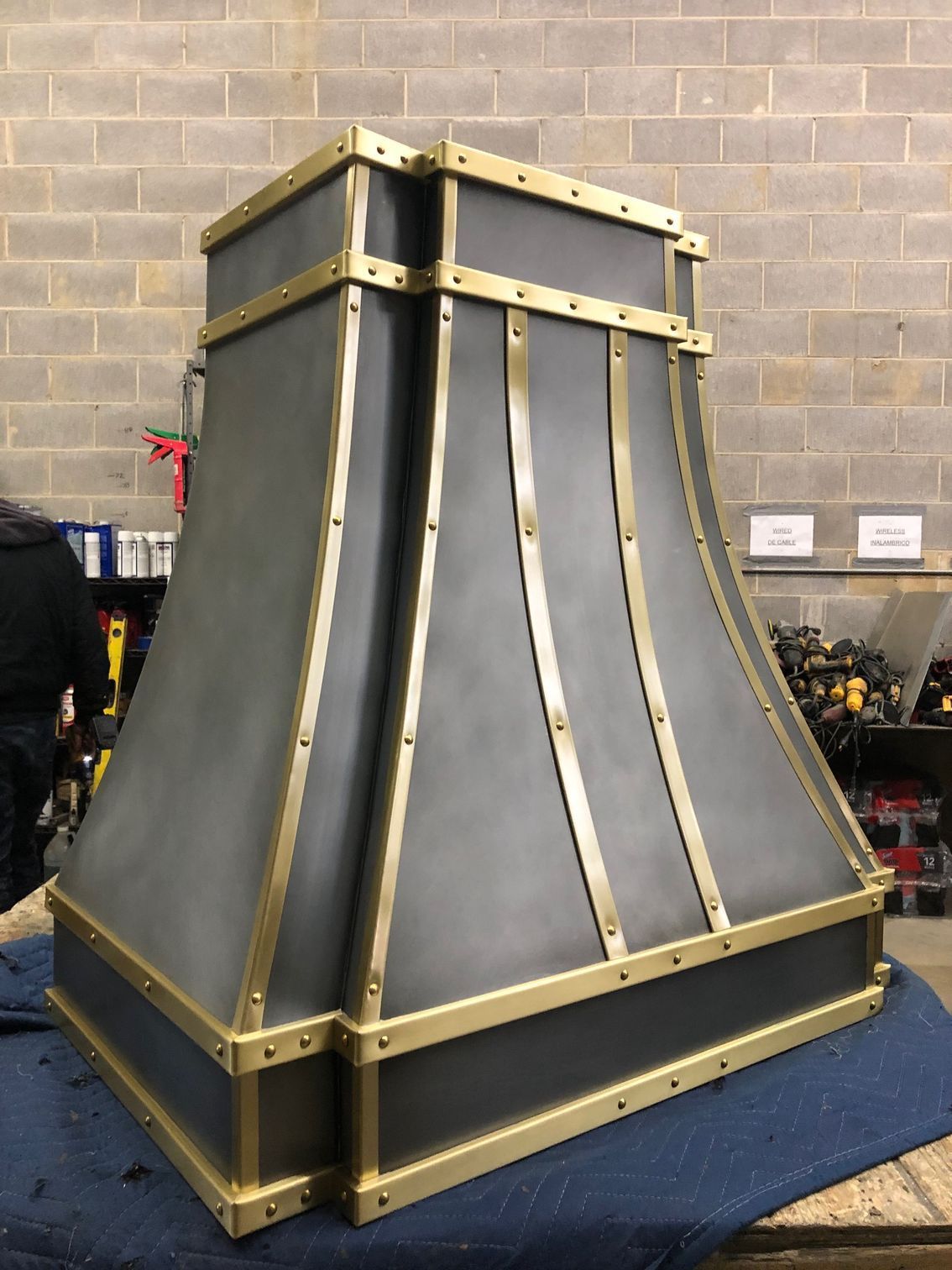Large black and gold metal structure on a blue tarp in a workshop or garage.