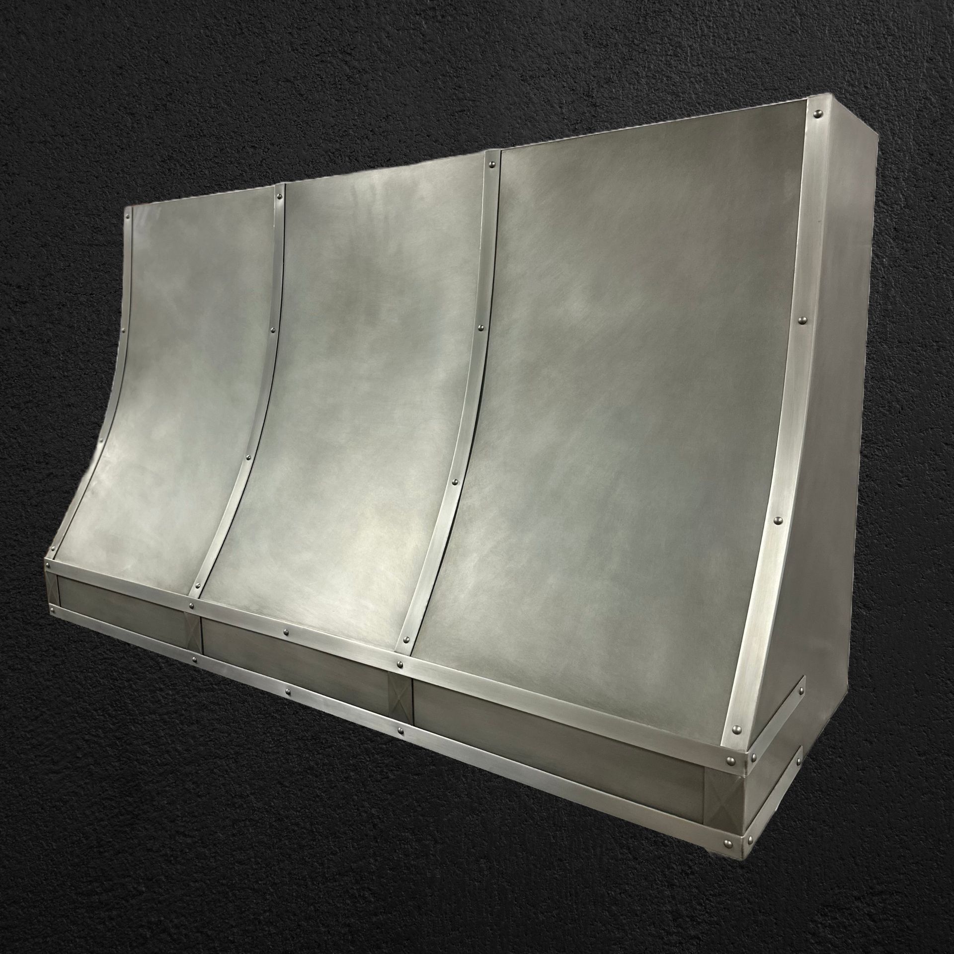 Metal industrial hood or duct cover with curved panels on a dark background