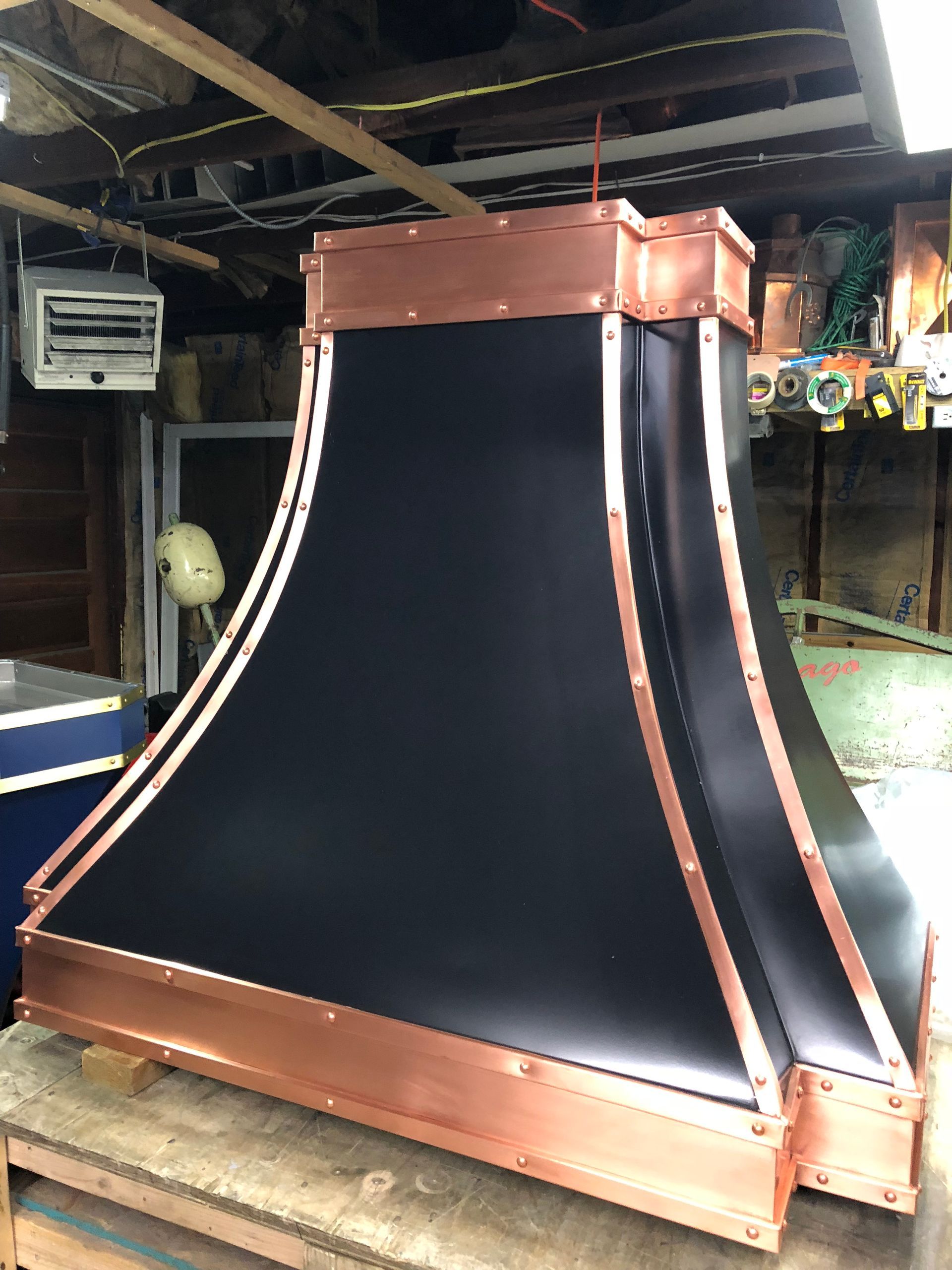 Large copper-and-black industrial funnel or chute in a workshop, with a sloped black fabric center.