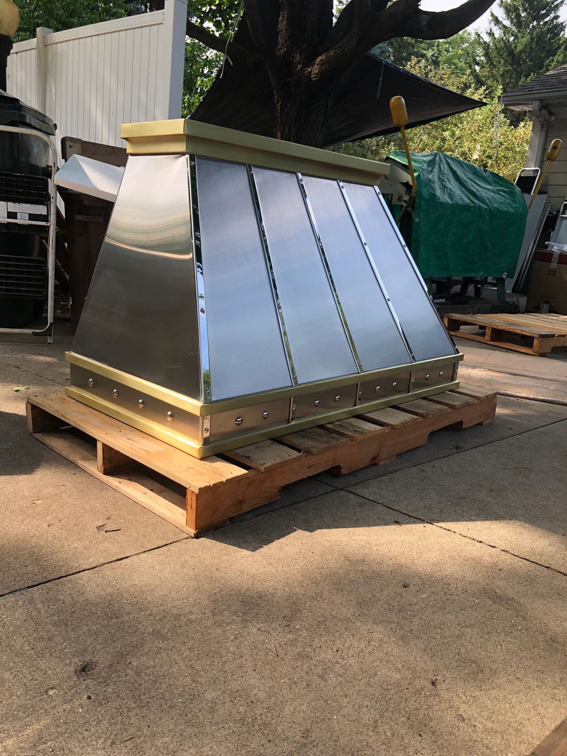 Metal chimney hood on a wooden pallet outdoors in a yard