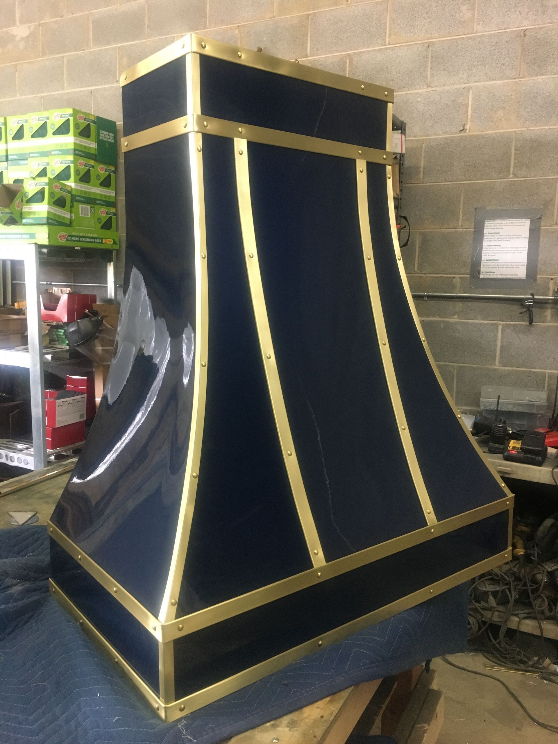 Large blue-and-gold fabric-covered structure with a flared base in a workshop