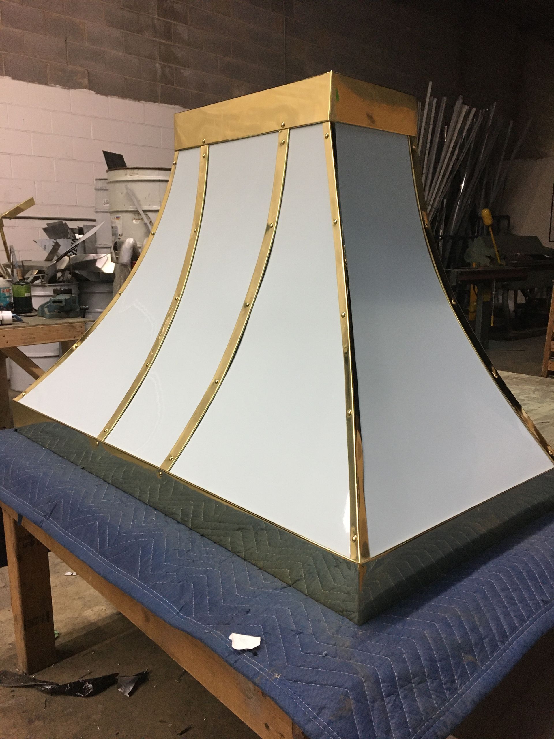 Gold-trimmed white architectural model on a blue-covered table in a workshop