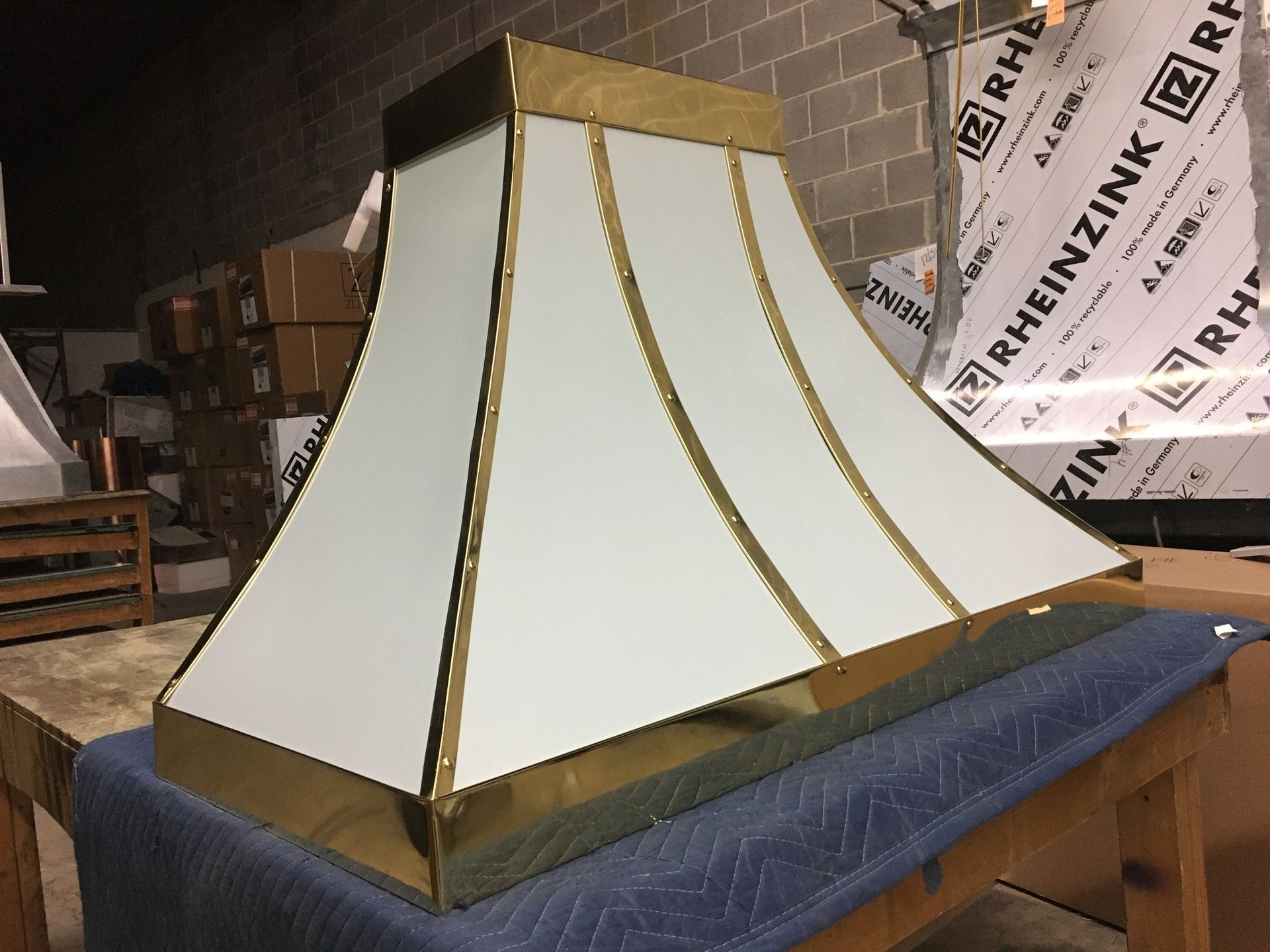 White tent-like display with gold trim on a table in a workshop or storage area