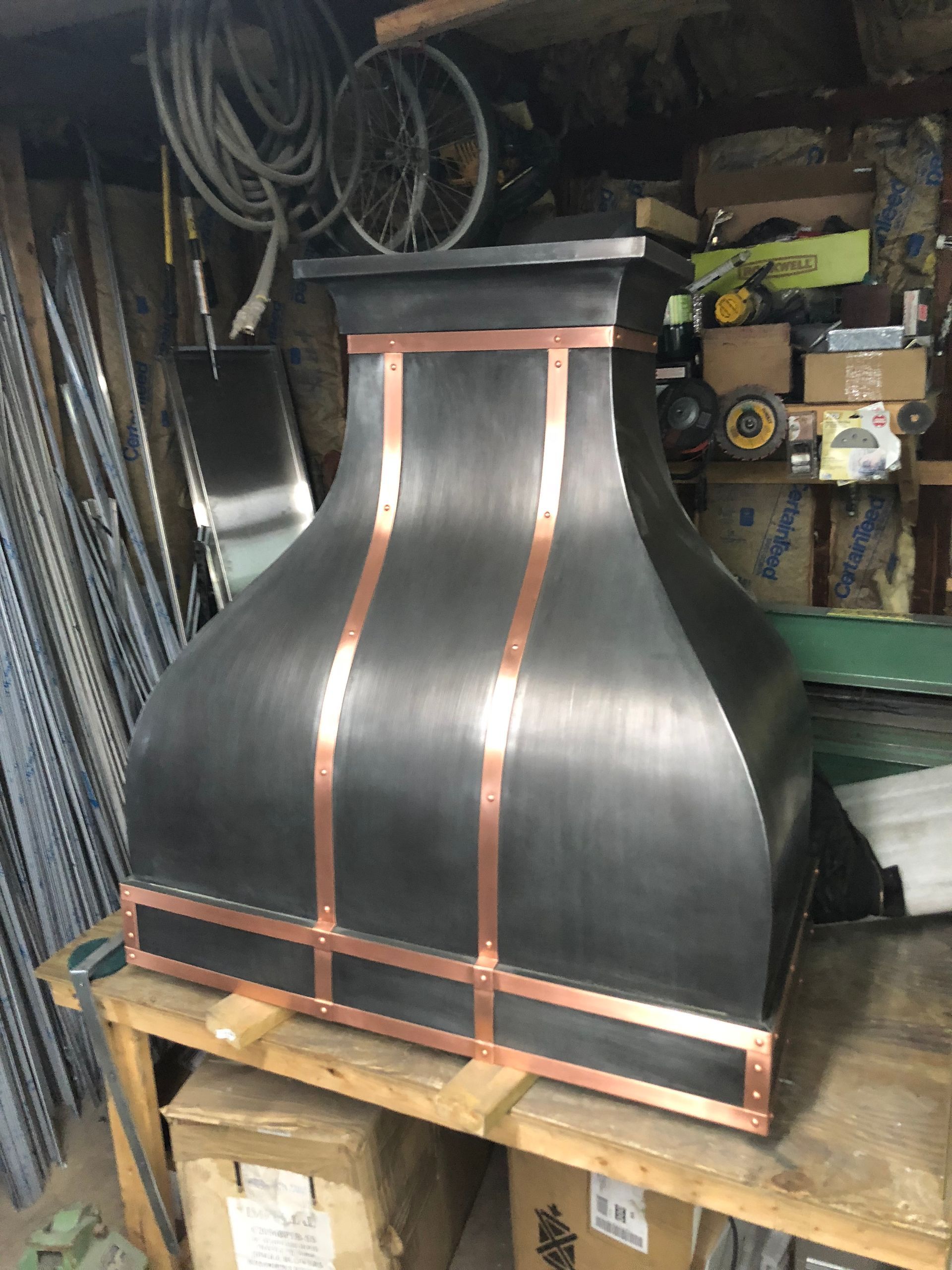 Black curved wooden panel with orange trim on a workbench in a workshop