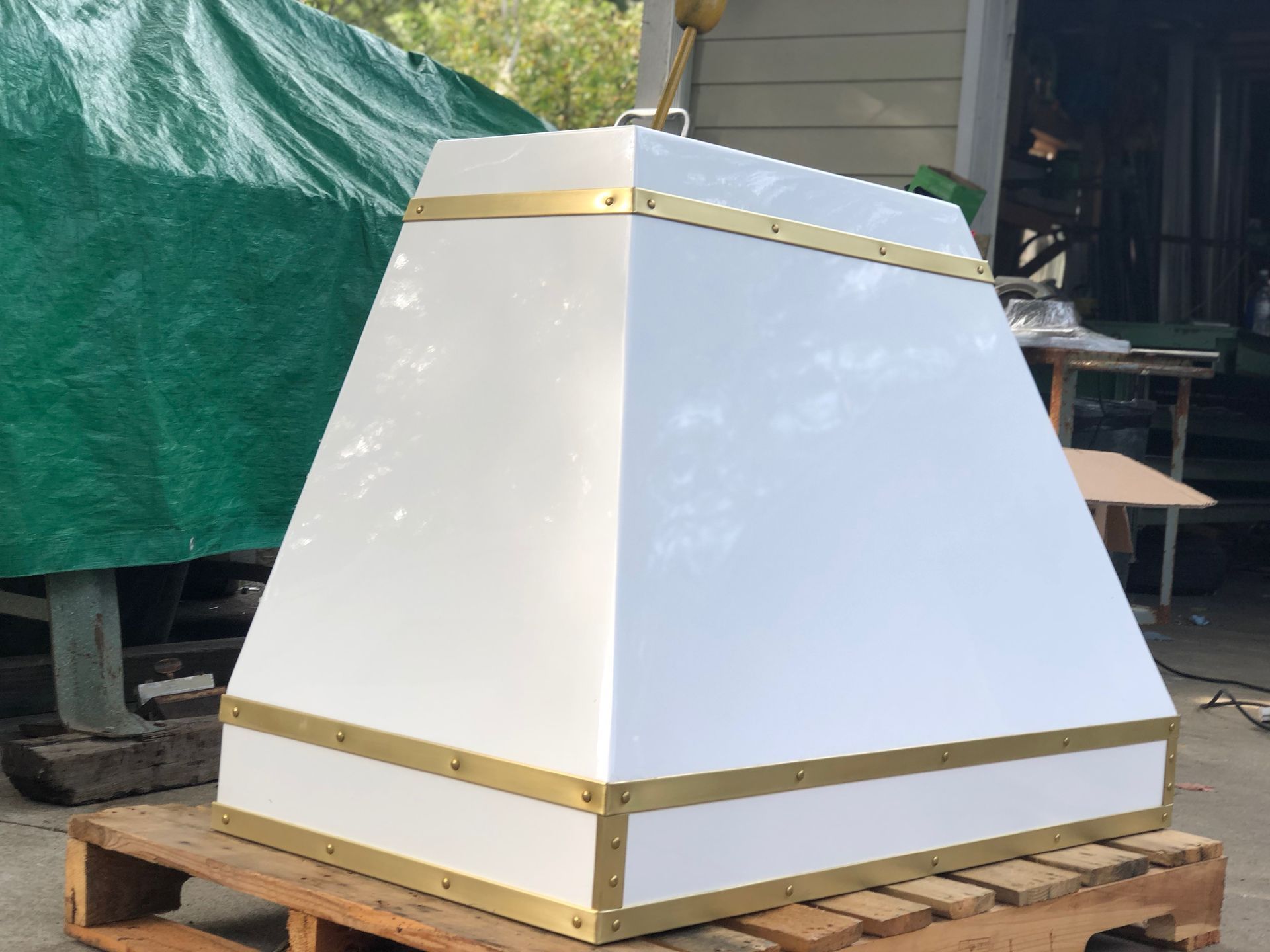 White trapezoidal wooden structure with gold trim sitting on a pallet outdoors