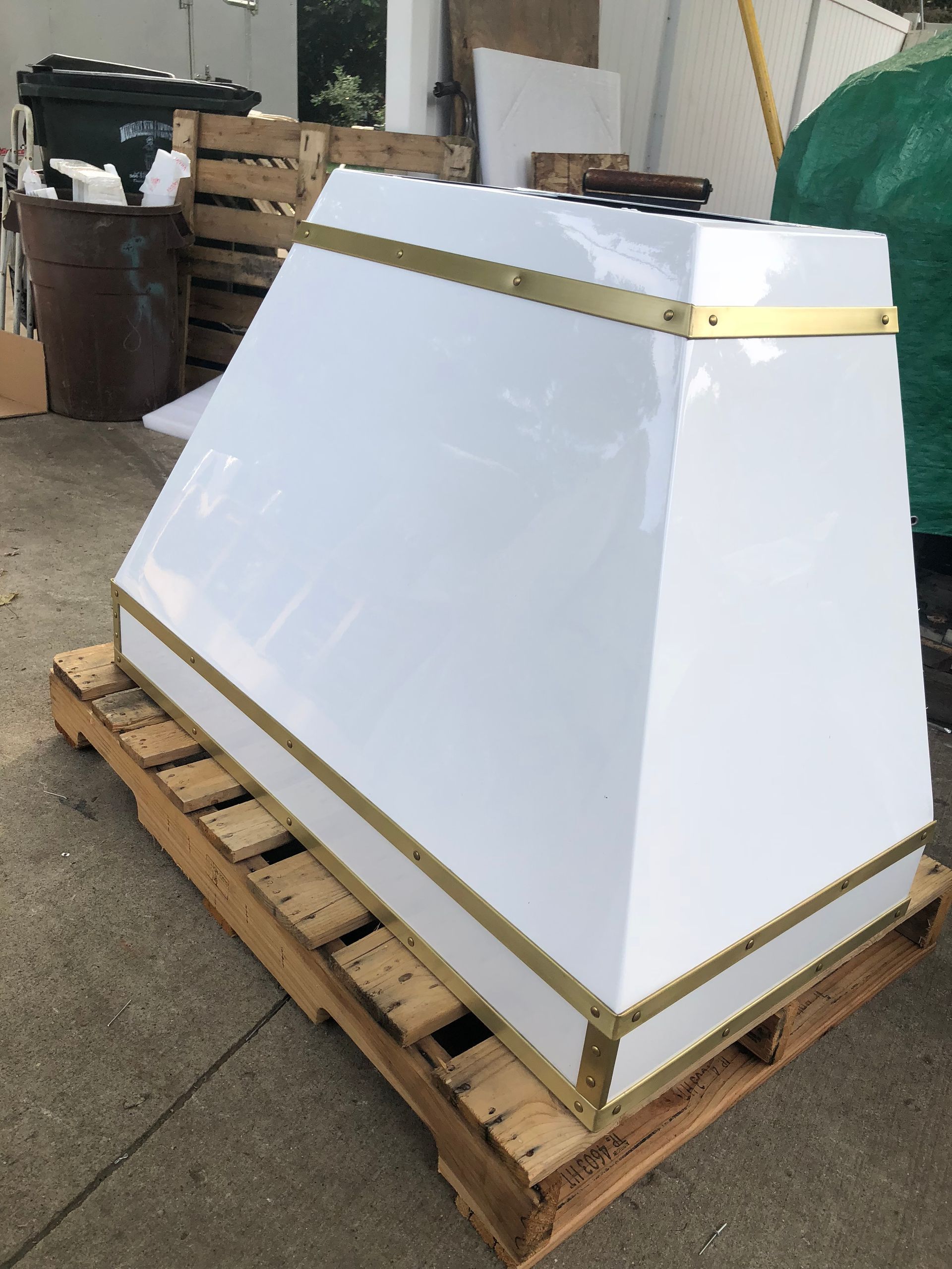 White beveled panel wrapped with gold tape, sitting on a wooden pallet in a warehouse area