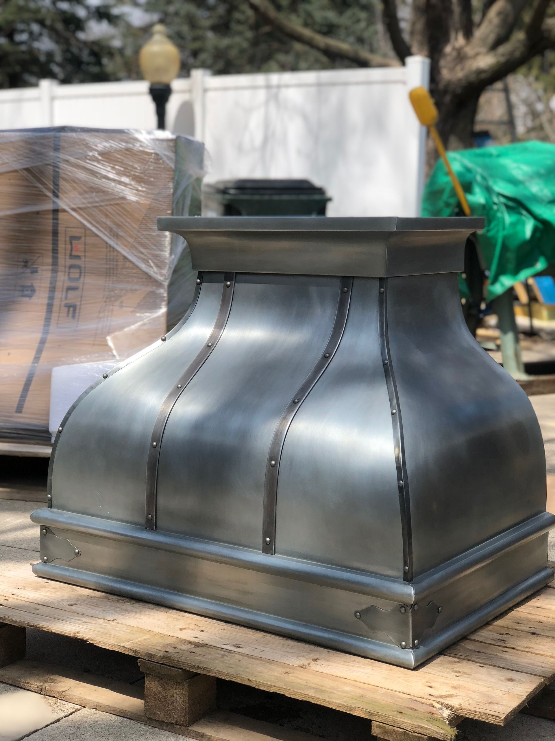 Large black metal rooftop vent sitting on a wooden pallet outdoors