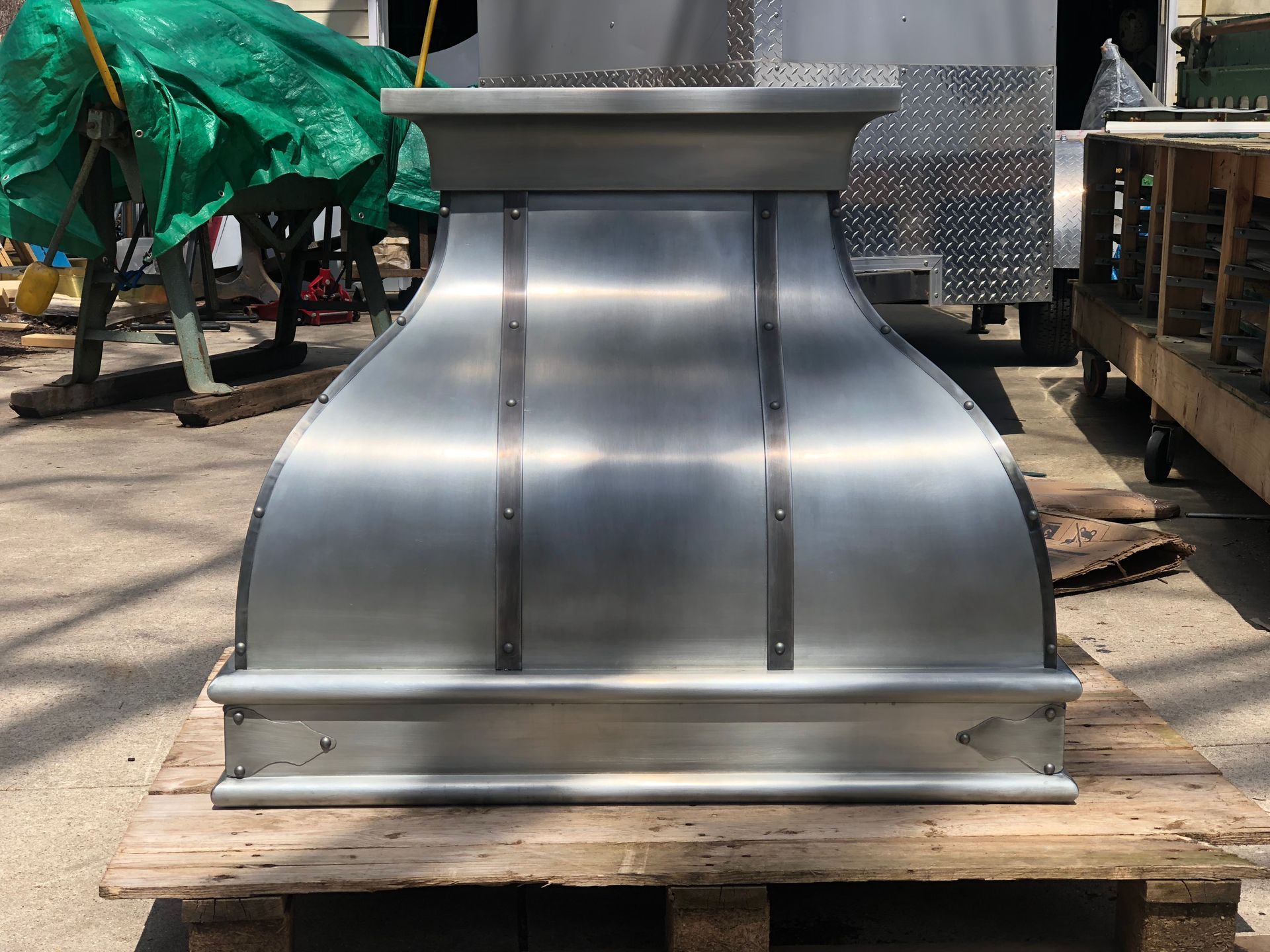 Large silver metal HVAC duct or vent hood sitting on a wooden pallet outdoors.