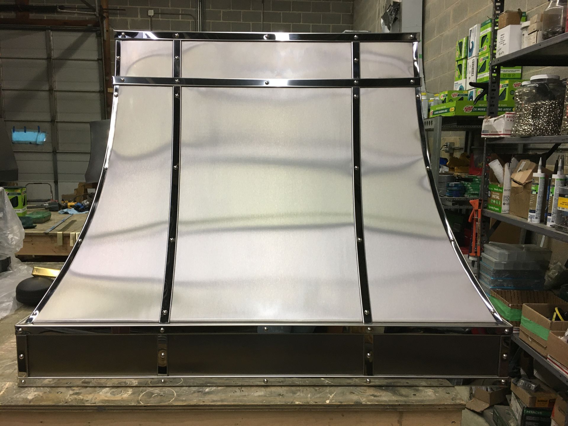 Large white metal ramp or chute with black supports in a warehouse workshop