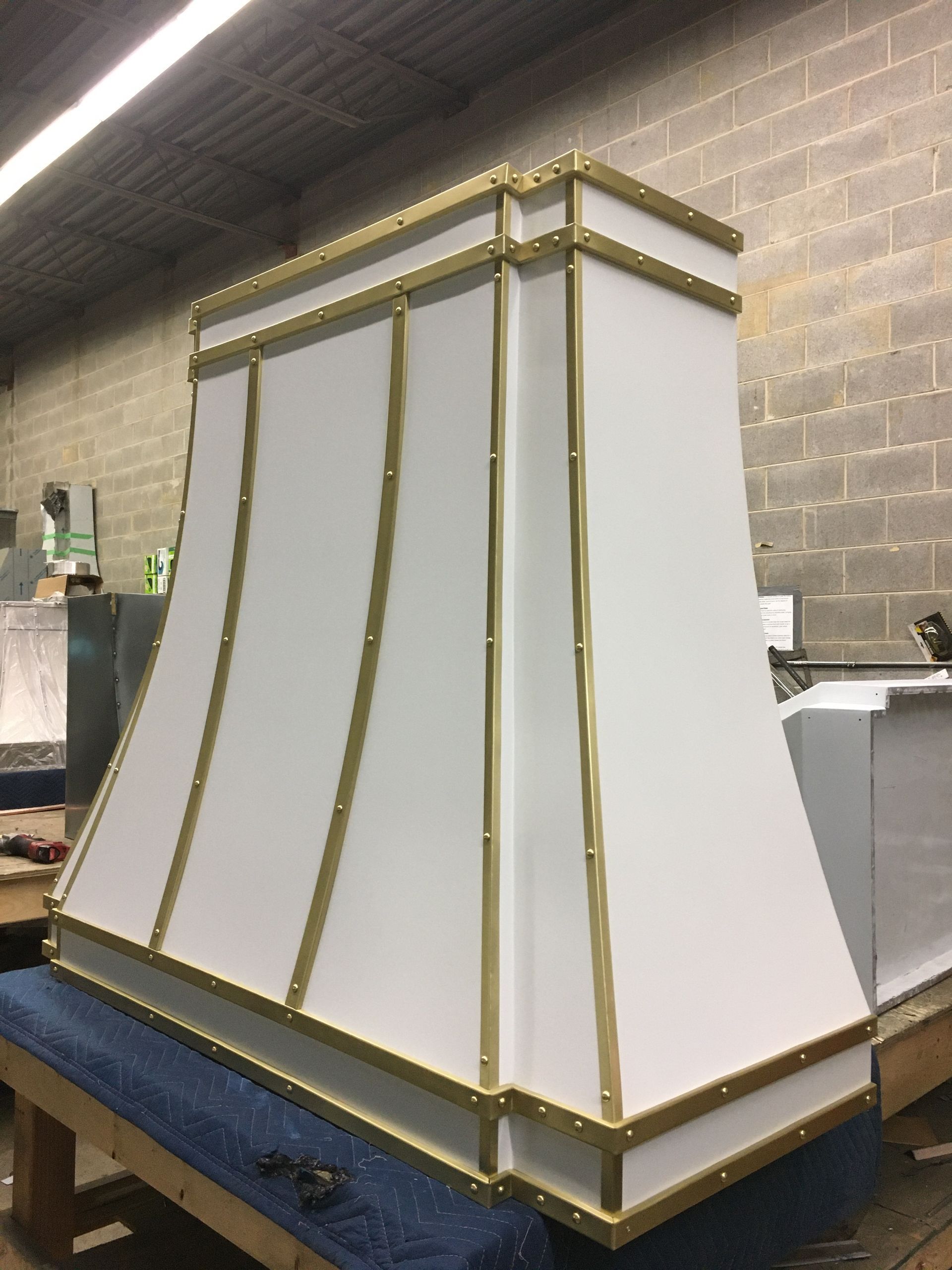 White decorative columned panel with gold trim, sitting in a workshop on a blue workbench.