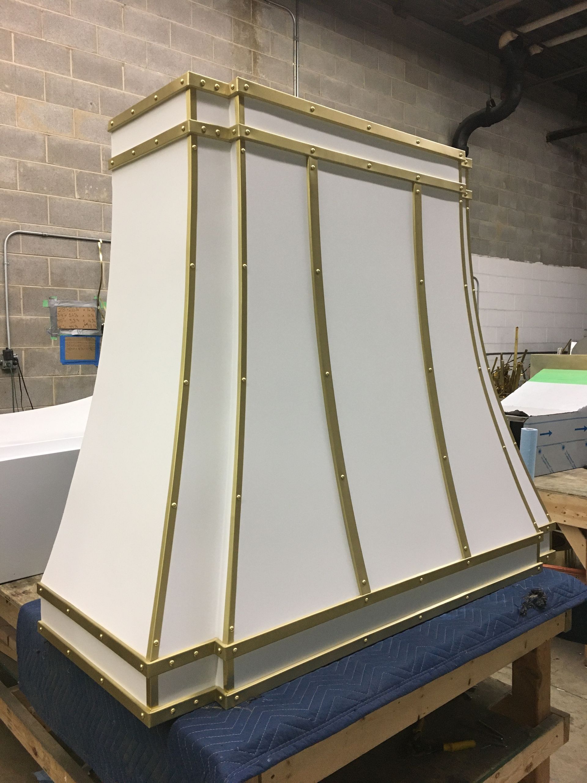 White tapered decorative box with gold trim on a workbench in a workshop