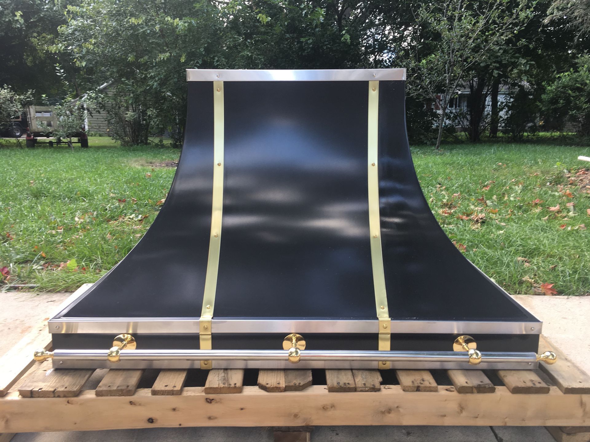 Black curved ramp or skate feature with yellow straps on a wooden pallet outdoors in a grassy yard