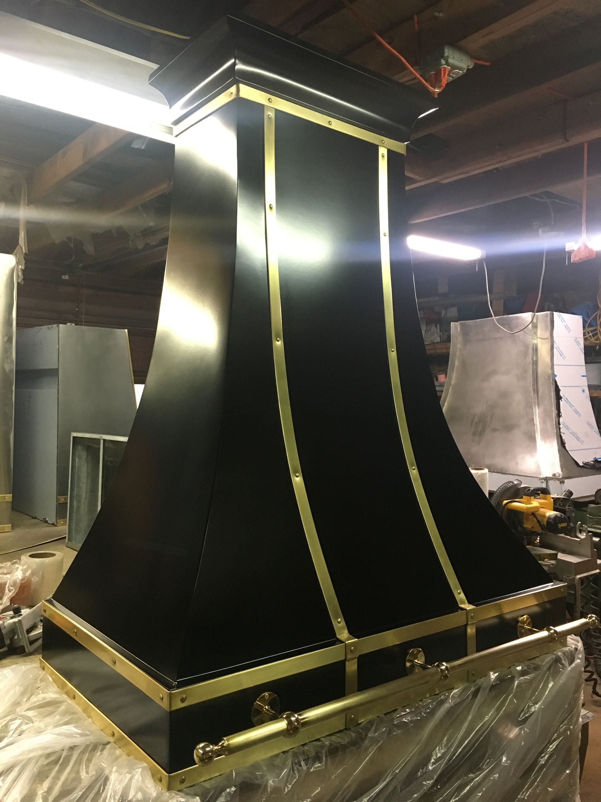 Black industrial chimney or duct with yellow trim in a workshop or factory setting