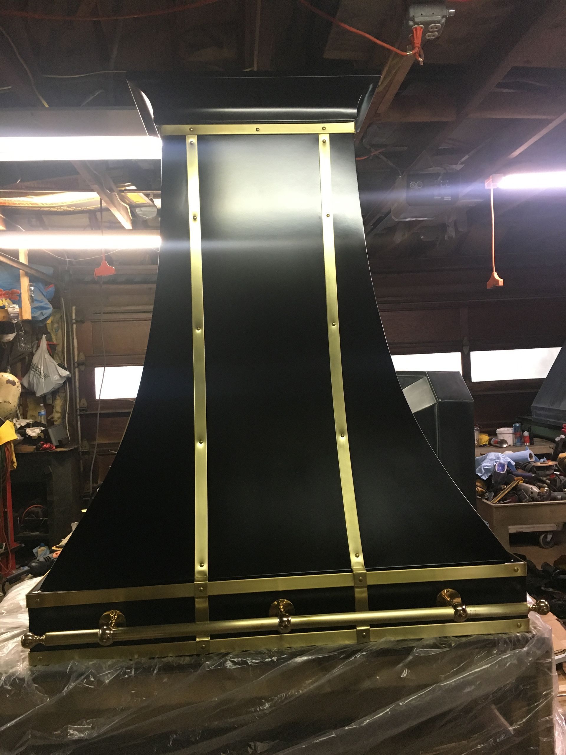 Large black-and-gold draped fabric panel hanging in an indoor workshop with exposed ceiling beams.