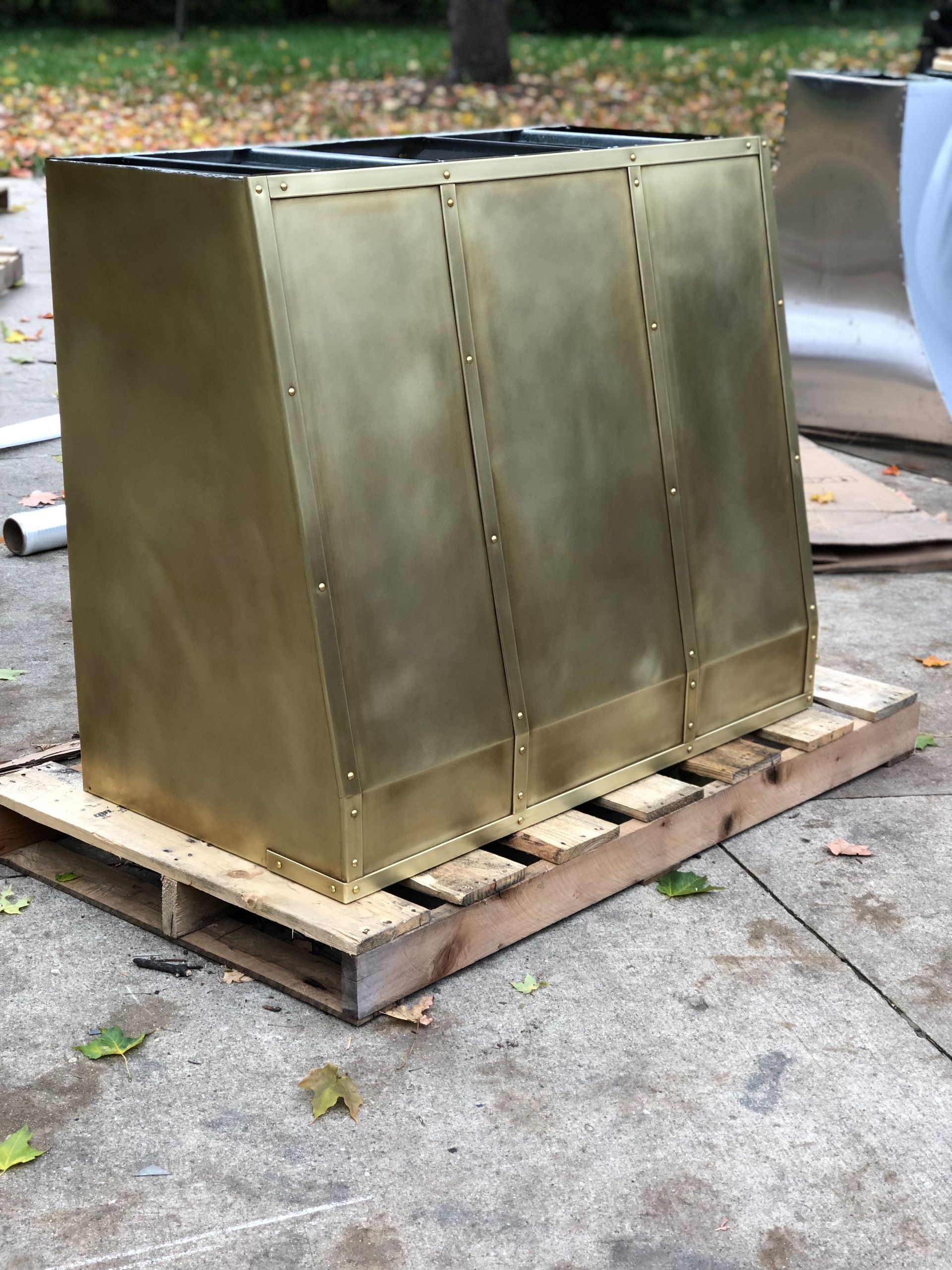 Brass-colored metal cabinet on a wooden pallet outdoors on a driveway