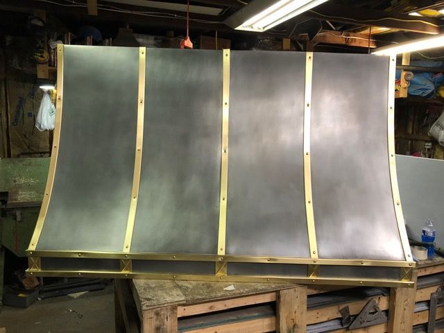Large curved metal panel with vertical gold-colored supports in an industrial workshop