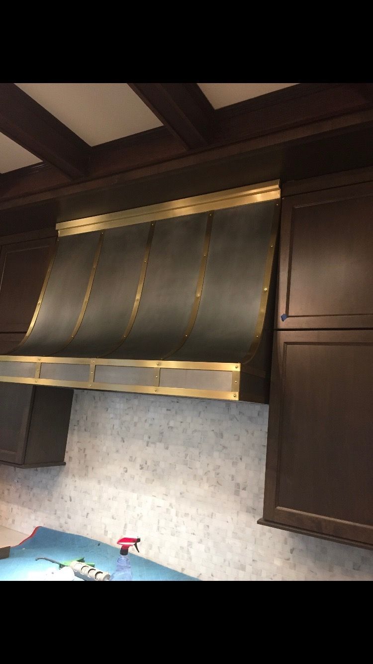 Modern kitchen with dark wood cabinets, stainless range hood, and blue countertop with a red faucet