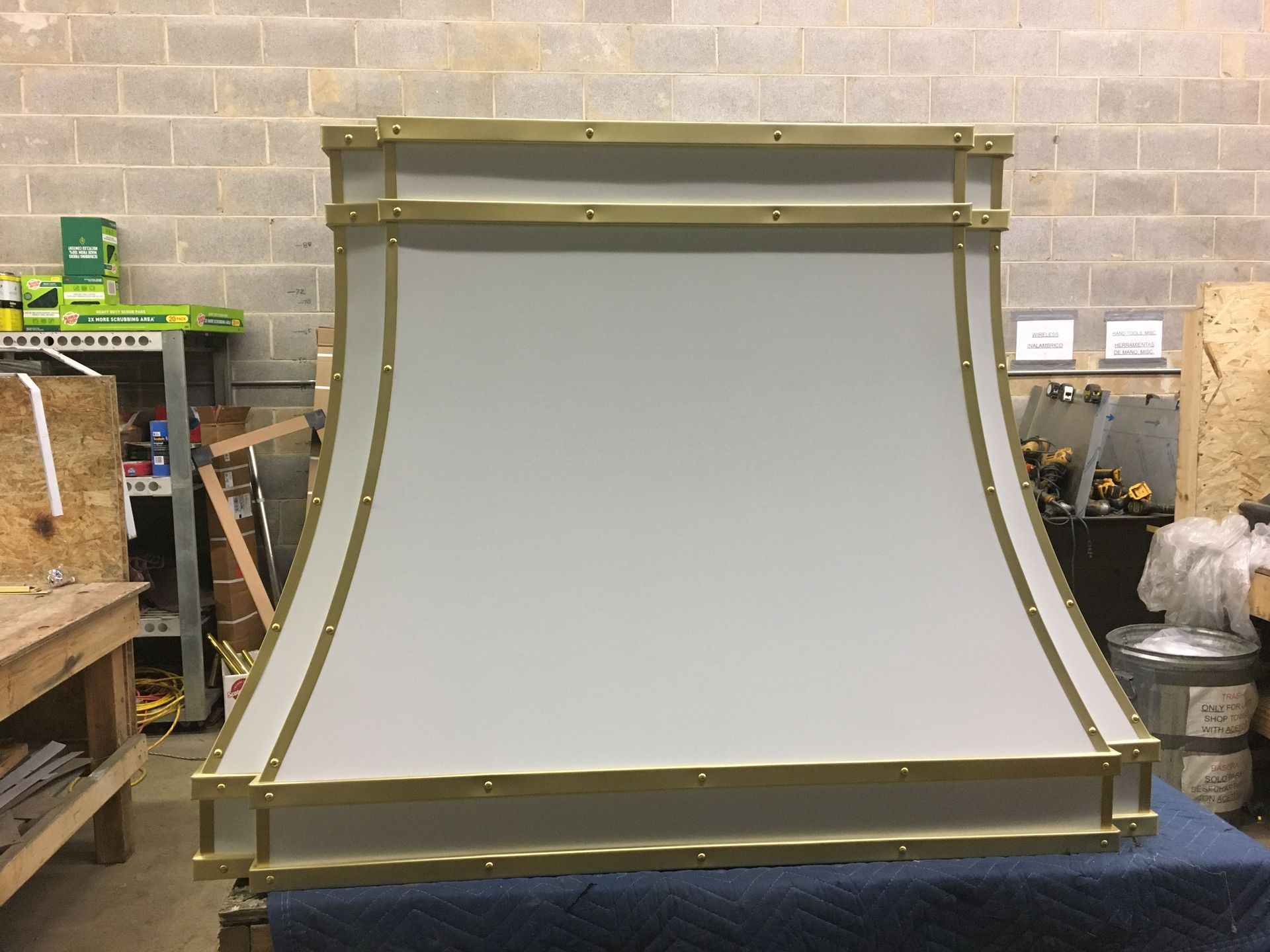 Large gray industrial panel with gold frame in a workshop against a brick wall
