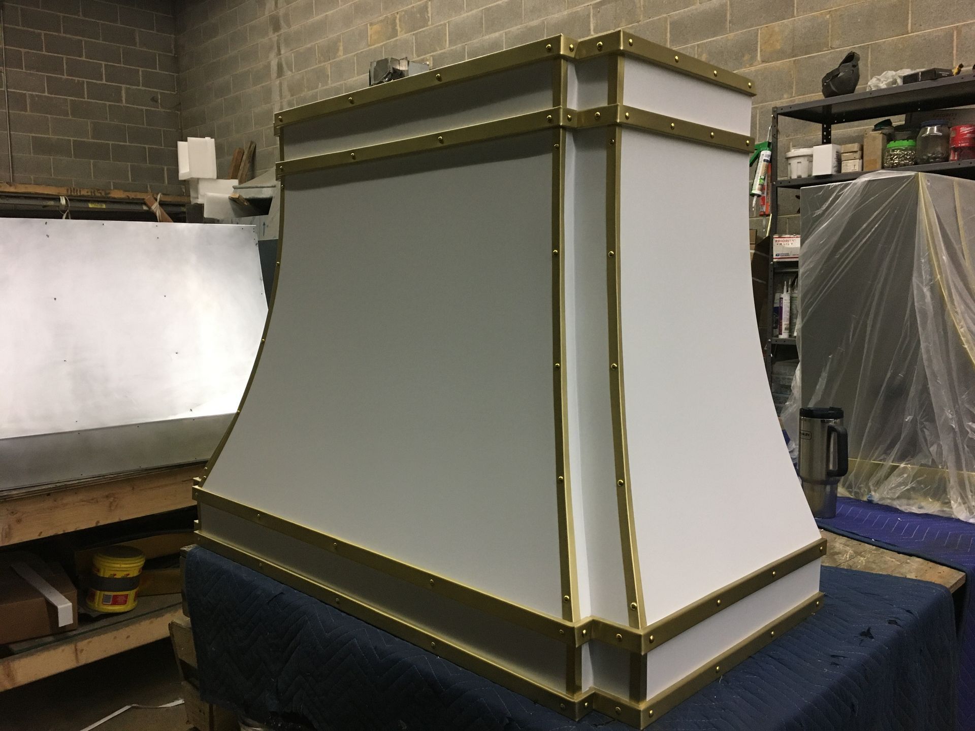 Large gray and white decorative cabinet or panel with gold trim in a workshop