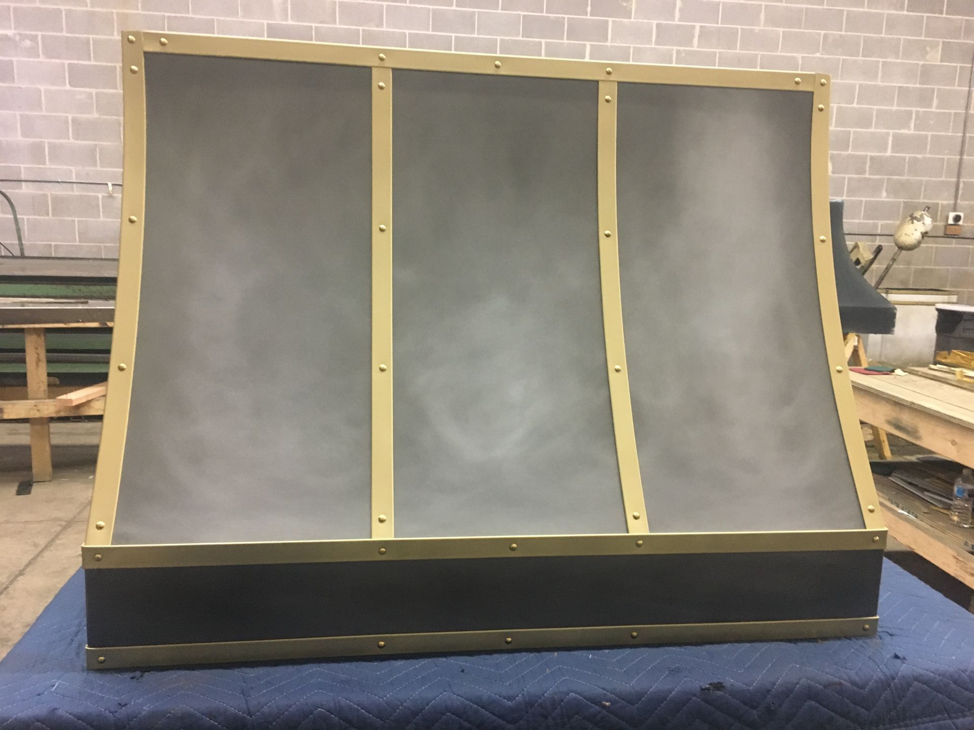 Three-panel curved black display wall with gold trim in a workshop