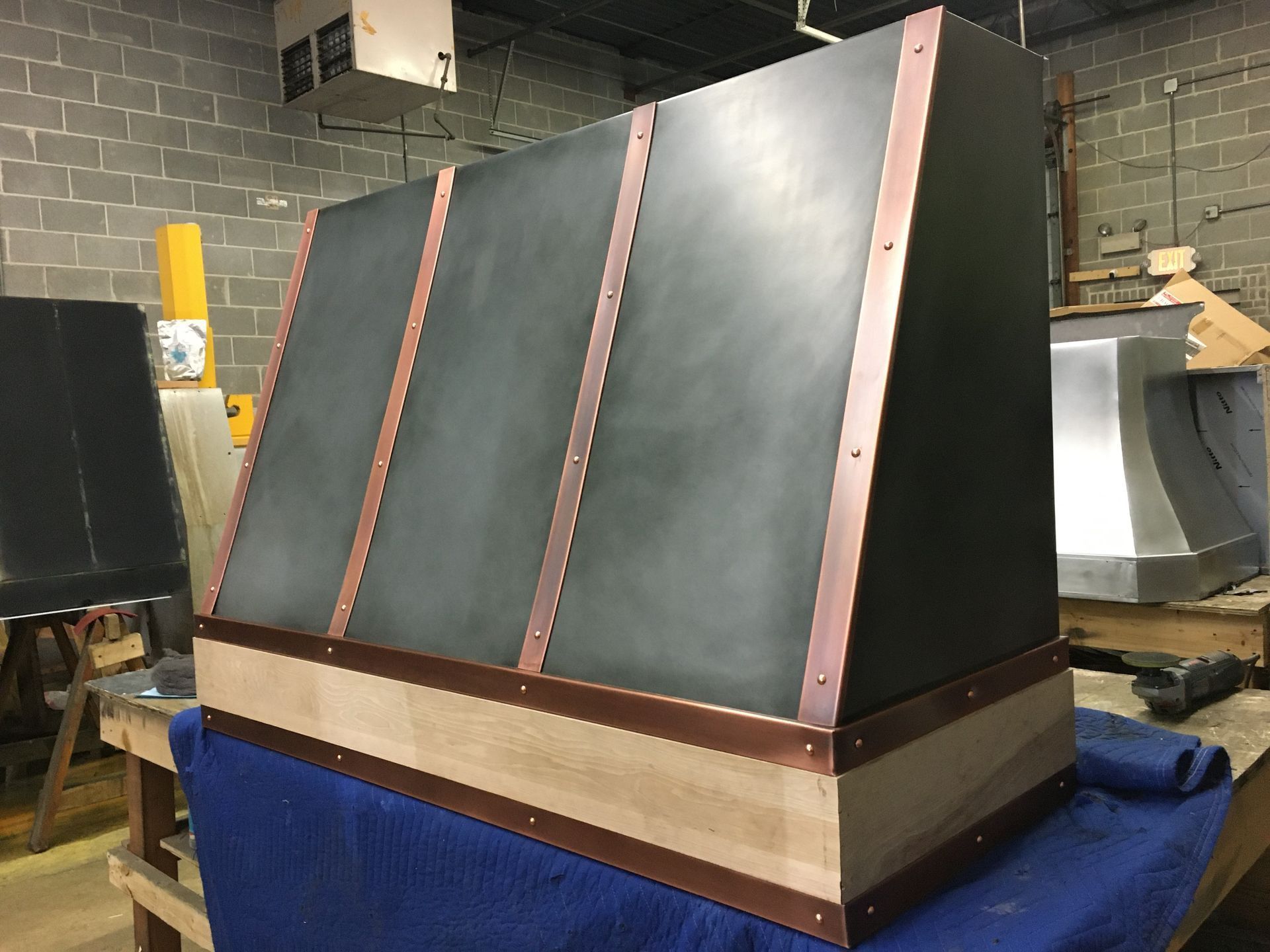 Black slanted industrial panel with copper trim on a wood base in a workshop