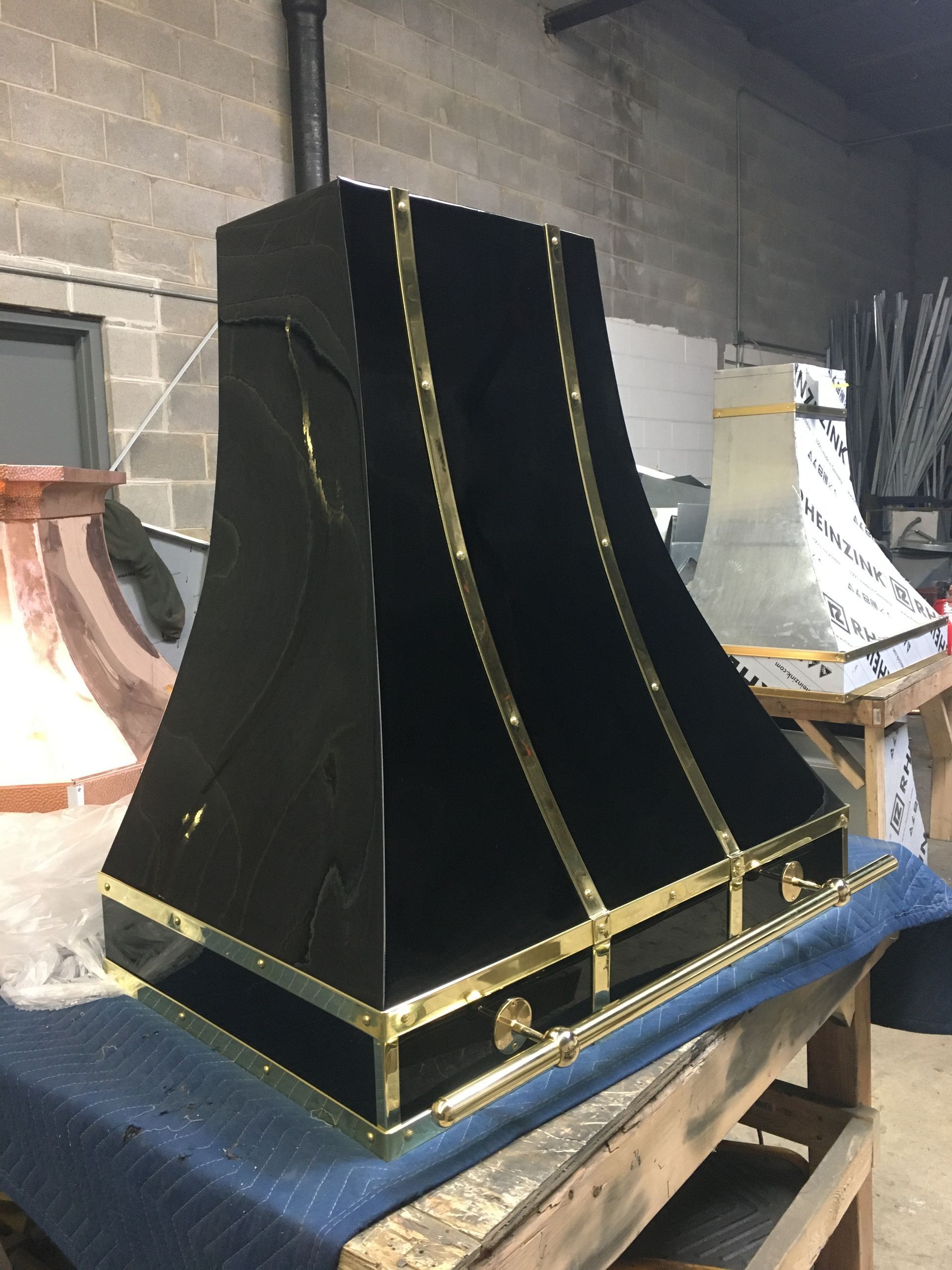 Black and gold ornate display piece on a blue table in a workshop or storage area